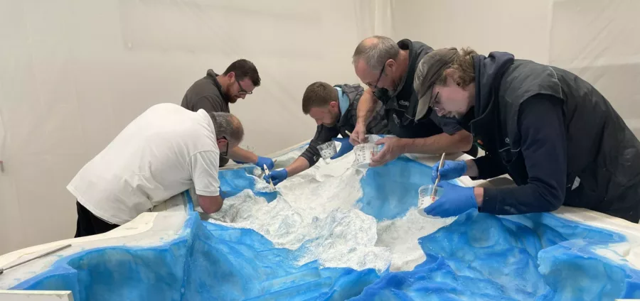 Visuel présentant des employés de Creaform en train de travailler sur un moule au fond bleu