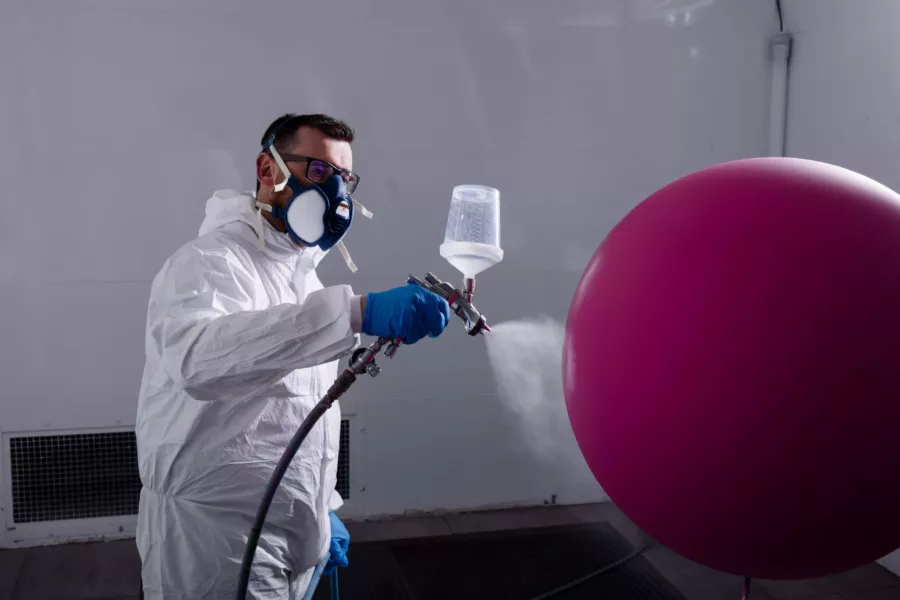 Visuel présentant un employé Creaform appliquant de la peinture sur un ballon rose dans une cabine peinture