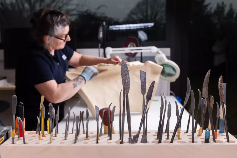 Visuel présentant une employée Creaform qui travaille derrière des outils servant à différentes techniques industrielles